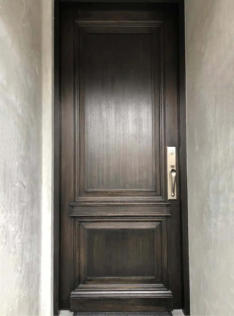 Wooden exterior doors with intricate carvings and brass doorknobs